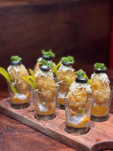 un tas de nourriture dans des verres en verre sur un plateau en bois dans l'établissement Hotel Virgo Sumeru, à Bhavnagar
