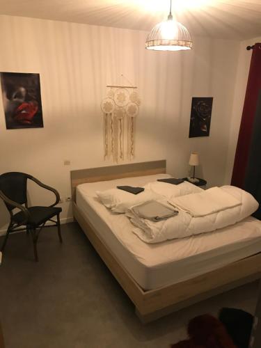 une chambre avec un grand lit et une chaise dans l'établissement Cœur de ville, à Mont-de-Marsan