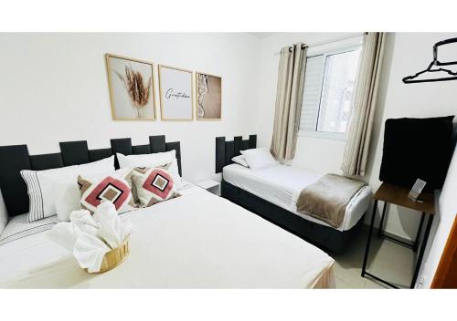 1 dormitorio con 2 camas con almohadas rosas en Portal das Palmeiras 2, en Ubatuba