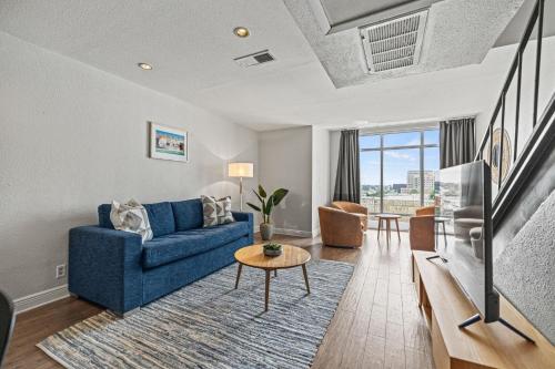 a living room with a blue couch and a tv at Littlefield Lofts, Hosted by Placemakr - 6th St in Austin