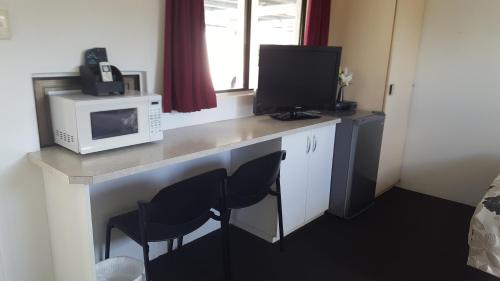 a room with a desk with a microwave and a microwave at Glenlyon Lodge - Gladstone in Gladstone