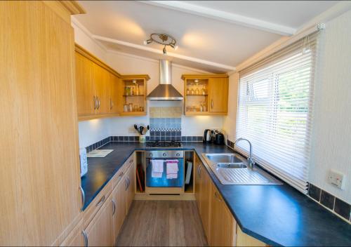 a kitchen with wooden cabinets and a sink at 11 The Oaks - Lodge - Coghurst Hall - Hastings in Westfield