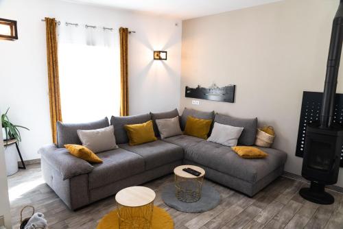 a living room with a gray couch and yellow pillows at La Maison de Jade & Spa in La Roche-de-Glun