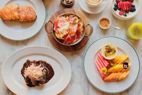una mesa cubierta con platos de comida y postres en The Madrid EDITION, en Madrid