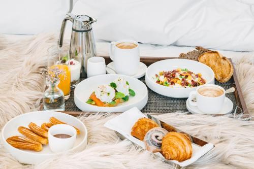 bandeja de alimentos para el desayuno y café en una cama en The Madrid EDITION, en Madrid