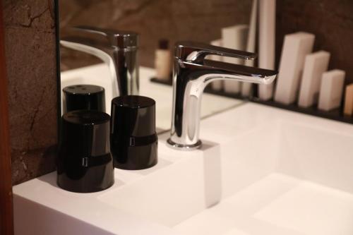 a bathroom sink with two cups and a faucet at BRĂAT Hôtel in Rabat