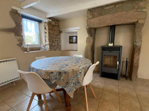 une salle à manger avec une table et des chaises et une cheminée dans l'établissement Maison de pêcheur avec terrasse à 450m de la plage à TREGASTEL - Réf 184, à Trégastel
