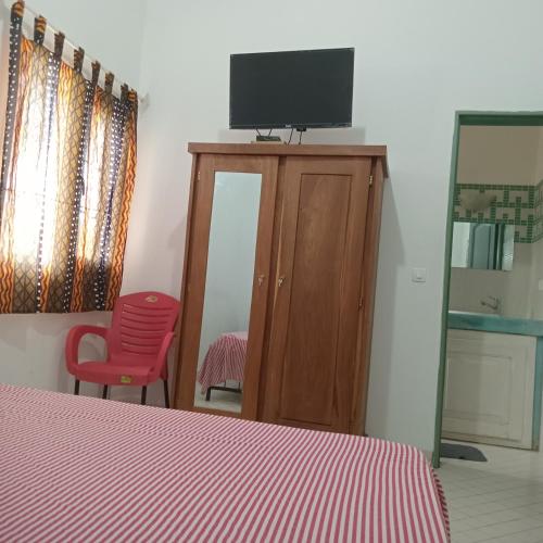 a bedroom with a bed and a tv on top of a cabinet at KEUR DIAM - Maison de la Paix in Saly Portudal