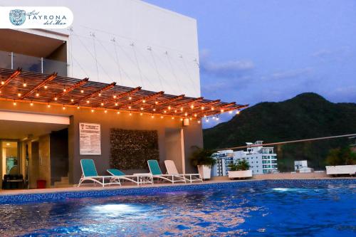 a hotel swimming pool with chairs and a building at Hotel Tayrona del Mar in Santa Marta