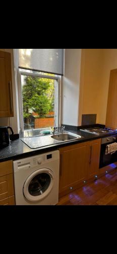 a kitchen with a sink and a washing machine at Hampden Hüs in Glasgow