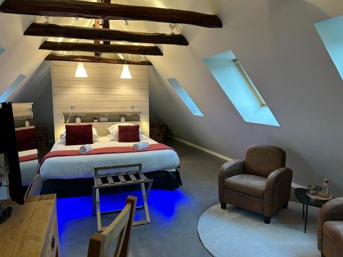 a attic bedroom with a bed and a chair at Logis Hôtel de Paris in Murol