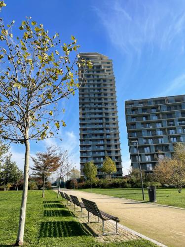 a row of benches in a park with a tall building at @UptownLiving in Pero
