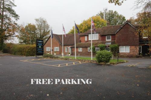 a building with flags in front of a parking lot at Trivelles Waterhall Country Gatwick Hotel & airport parking in Crawley