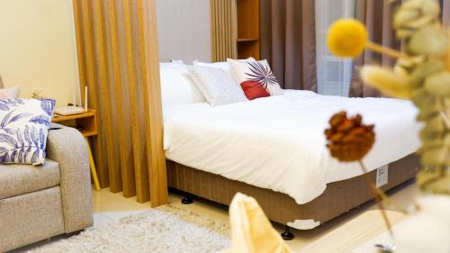 a bedroom with a bed with white sheets and pillows at New Cozy Condo in Eastwood in Manila