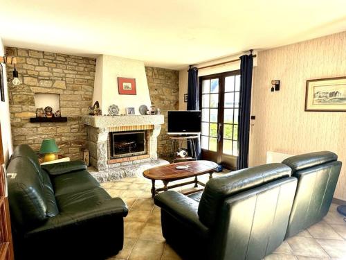 Elle comprend un salon doté d'un mobilier en cuir et d'une cheminée. dans l'établissement Ker-Neo Maison familiale bretonne - Etel, à Étel