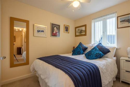 a bedroom with a bed with blue pillows and a mirror at Charming Essex Hideaway in Southend-on-Sea