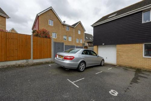 a silver car parked in a parking lot next to houses at Charming Essex Hideaway in Southend-on-Sea