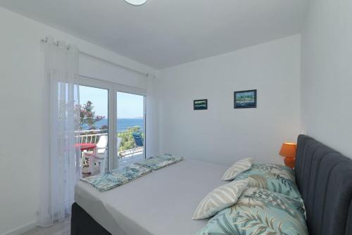 a bedroom with a large bed and a balcony at Apartment Zamalin SeaView in Tribunj