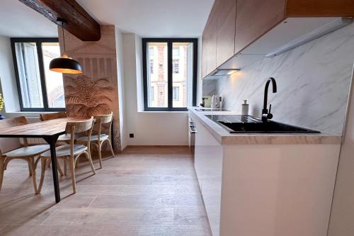 a kitchen with a sink and a table with chairs at MACE Appartement avec SPA dans quartier Historique Exclusif Calme Coeur d'Antibes in Antibes