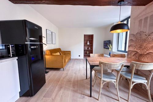 a kitchen and dining room with a black refrigerator and a table at MACE Appartement avec SPA dans quartier Historique Exclusif Calme Coeur d'Antibes in Antibes