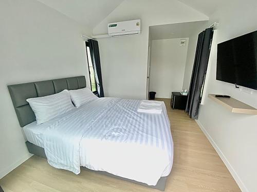 a bedroom with a white bed and a flat screen tv at สุขสวัสดิ์ มินิรีสอร์ท in Ban Long