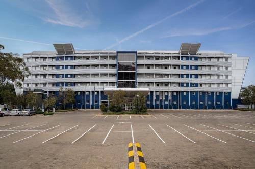 a large building with a parking lot in front of it at Protea Hotel by Marriott O R Tambo Airport in Kempton Park
