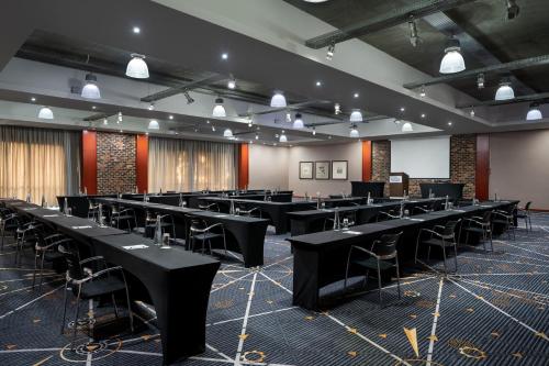 a large room with black tables and chairs at Protea Hotel by Marriott O R Tambo Airport in Kempton Park