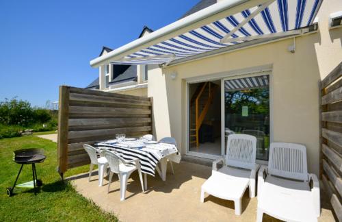 un patio avec une table et des chaises blanches et un aearcherearcherearcher dans l'établissement Le Clos de la Plage TY FANCH, à Erdeven