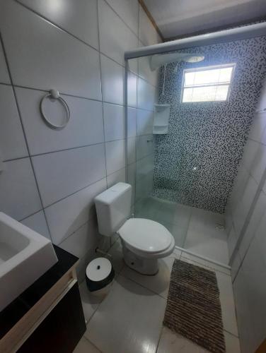 a bathroom with a toilet and a shower and a sink at Canto da Aracuã in Praia do Rosa