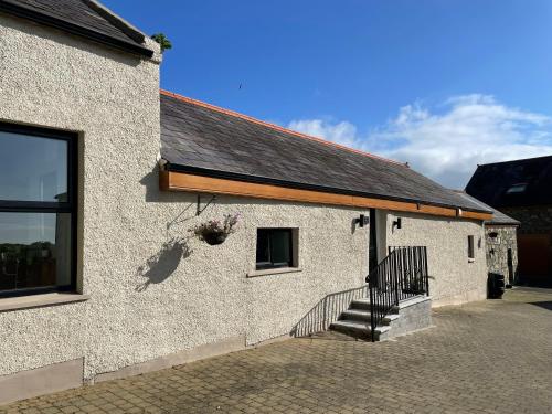 a white building with a staircase on the side of it at Grange Cottage in Ballynoe
