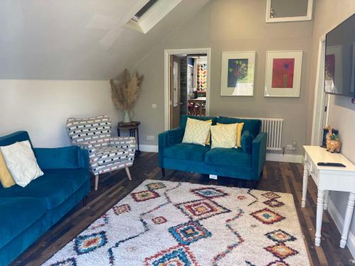 a living room with two blue couches and a rug at Lime Tree Cottage in Tillingham