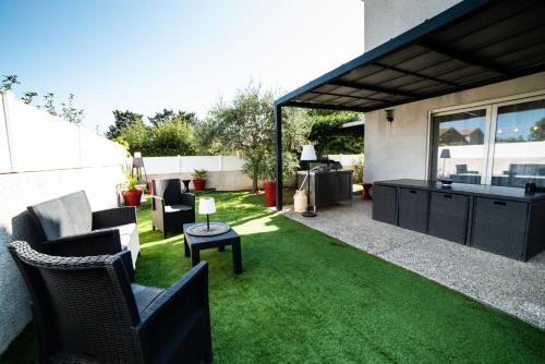 a patio with chairs and a table and grass at La Maison de Jade & Spa in La Roche-de-Glun