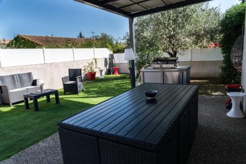 a backyard with a black table and a grill at La Maison de Jade & Spa in La Roche-de-Glun