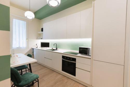 Una cocina con gabinetes blancos y una mesa y un microondas. en Cozy olive green flat, en Florencia