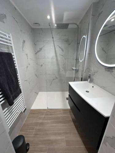 une salle de bain blanche avec un lavabo et un miroir dans l'établissement Maison de bourg bretonne, à Baulon