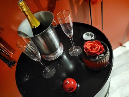Una mesa negra con vasos y una botella de champán y una magdalena. en Love room xoxo, en Norrois