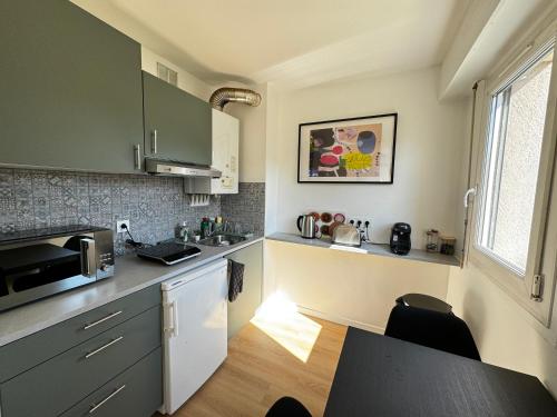 une cuisine avec un évier et un micro-ondes dans l'établissement Un cocon en plein centre ville, à Osny