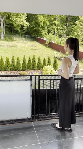 a woman standing on a balcony looking at a park at PerfectSpa Wellness Apartment in Humenné