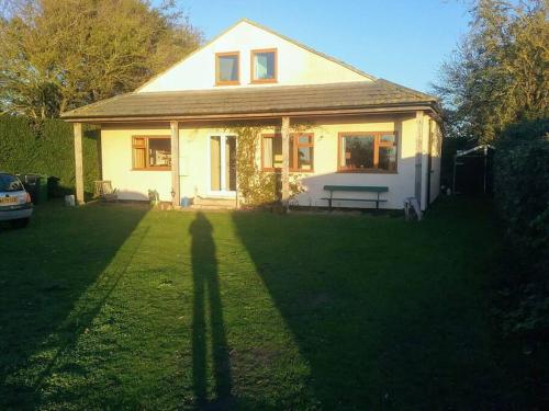 a small white house with a bench in the yard at The Patch at Snettisham Beach in Snettisham