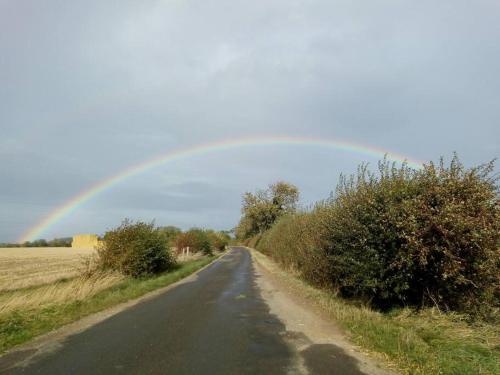 a rainbow in the sky over a road at The Patch at Snettisham Beach in Snettisham