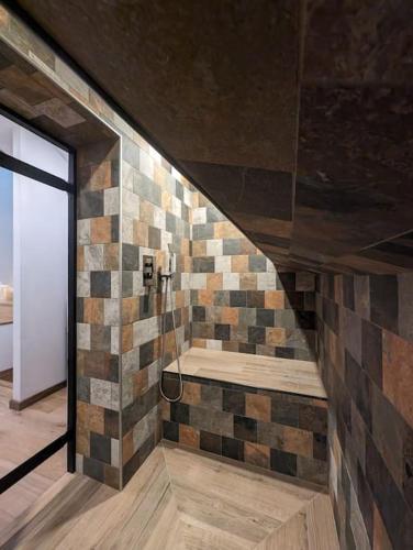 une salle de bain avec une douche avec un banc sur un mur dans l'établissement Luxueux chalet montagnard, à Isola 2000