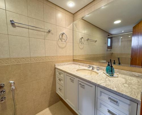 ein Badezimmer mit Waschbecken und Spiegel in der Unterkunft VV Suítes - Apto Rua Coberta in Gramado