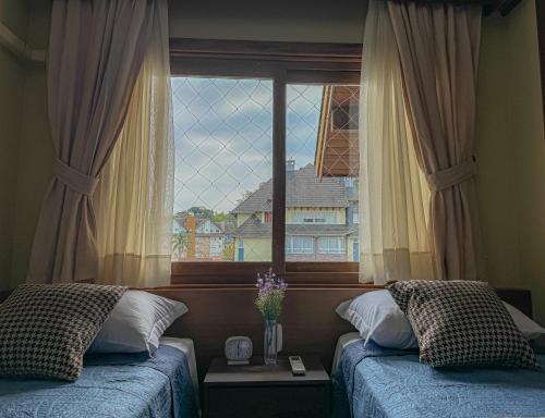 ein Schlafzimmer mit zwei Betten und einem großen Fenster in der Unterkunft VV Suítes - Apto Rua Coberta in Gramado