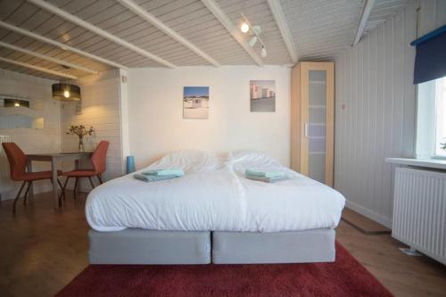 een slaapkamer met een groot wit bed en een tafel bij Stop & Stay 2 in Zandvoort