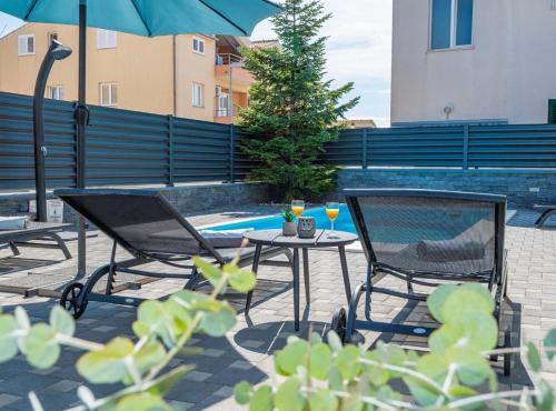 two chairs and a table with an umbrella next to a pool at Villa S in Vodice