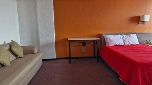 a bedroom with a red bed and a couch at Parador del Río by Flamingo Hotels Group in Irapuato