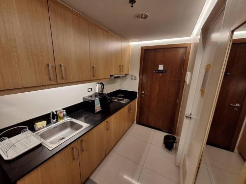a small kitchen with a sink and wooden cabinets at Best staycation at Shell residences in MOA complex in Manila