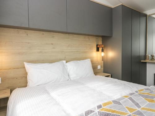 une chambre avec un lit blanc avec une tête de lit en bois dans l'établissement Elm, à Denny