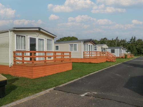 une maison avec une terrasse en bois à côté d'une rangée de maisons dans l'établissement Elm, à Denny