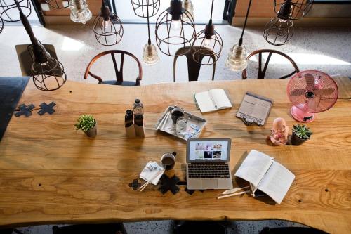 a wooden table with a laptop and books on it at MOXY Phoenix Tempe/ASU Area in Tempe